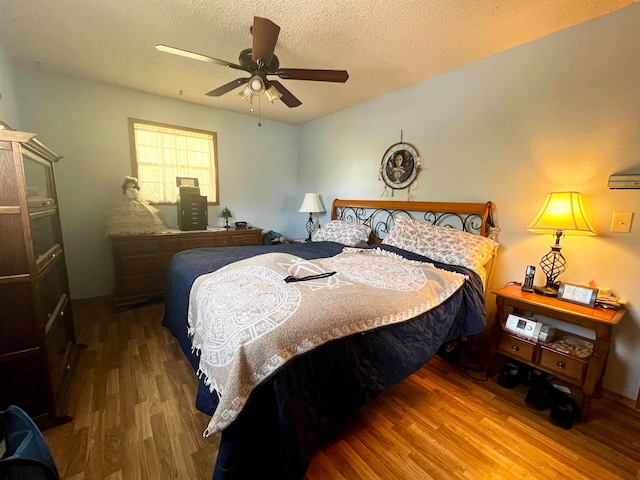 bedroom featuring a textured ceiling, wood-type flooring, and ceiling fan