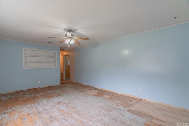 empty room featuring visible vents, built in features, a ceiling fan, wood finished floors, and crown molding