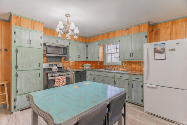 kitchen with a chandelier, light wood-style flooring, a sink, appliances with stainless steel finishes, and tasteful backsplash