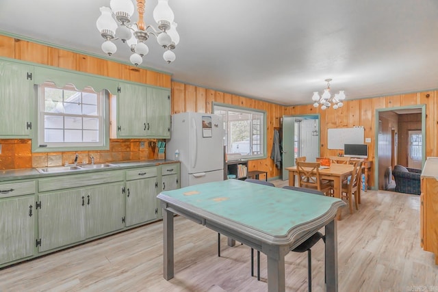 rec room with a chandelier, wood walls, light wood-type flooring, and a sink