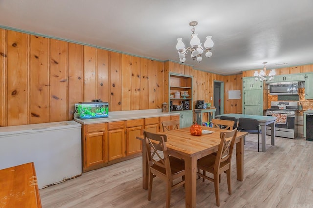 dining room with light wood-type flooring, a notable chandelier, and wooden walls