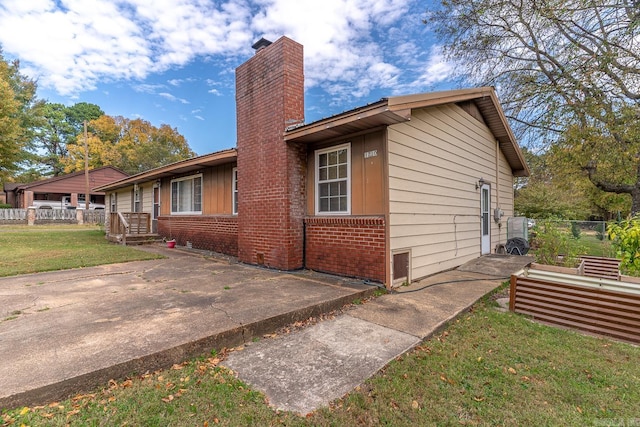 view of home's exterior featuring a yard, brick siding, a chimney, and fence