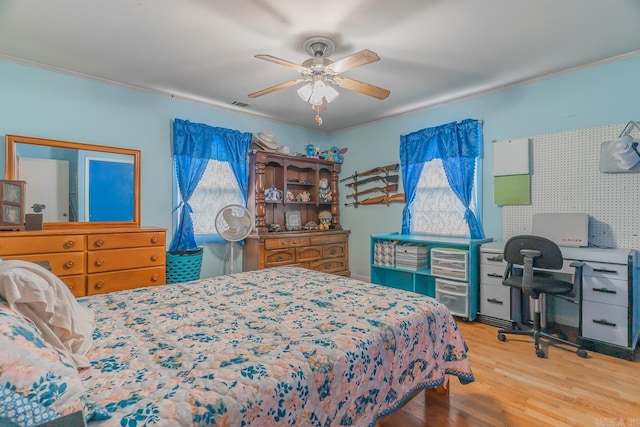 bedroom featuring a ceiling fan, visible vents, and wood finished floors