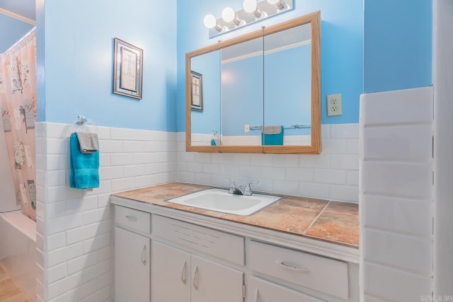 full bathroom with tile walls, a wainscoted wall, and vanity