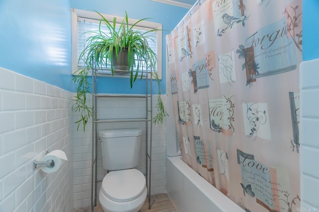 bathroom with wainscoting, shower / tub combo with curtain, tile walls, and toilet