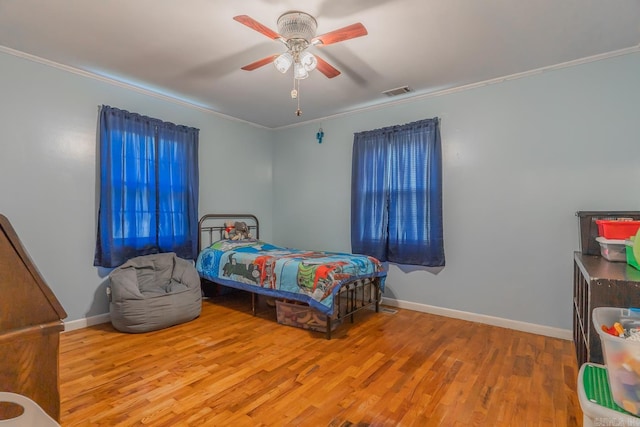 bedroom featuring baseboards, visible vents, ornamental molding, and wood finished floors