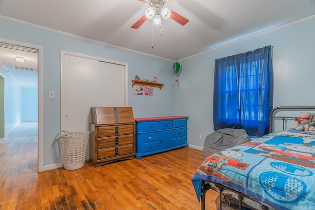 bedroom with light wood finished floors, ornamental molding, visible vents, and a ceiling fan