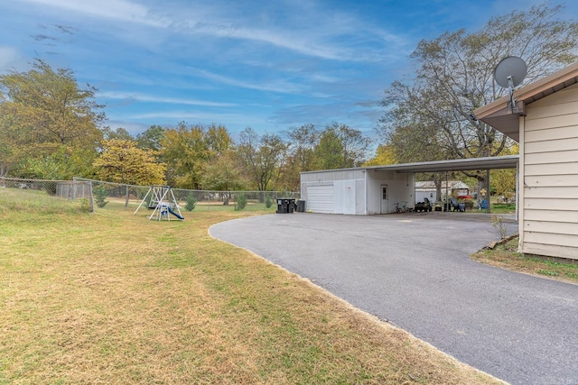 view of yard with a playground, fence, aphalt driveway, and a carport