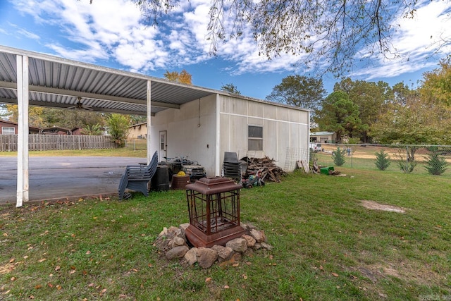 view of outdoor structure with driveway, fence, and a carport