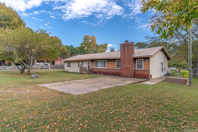 rear view of property with a patio, a chimney, fence, a yard, and brick siding