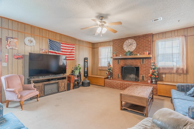 carpeted living room featuring plenty of natural light, a textured ceiling, a brick fireplace, and visible vents