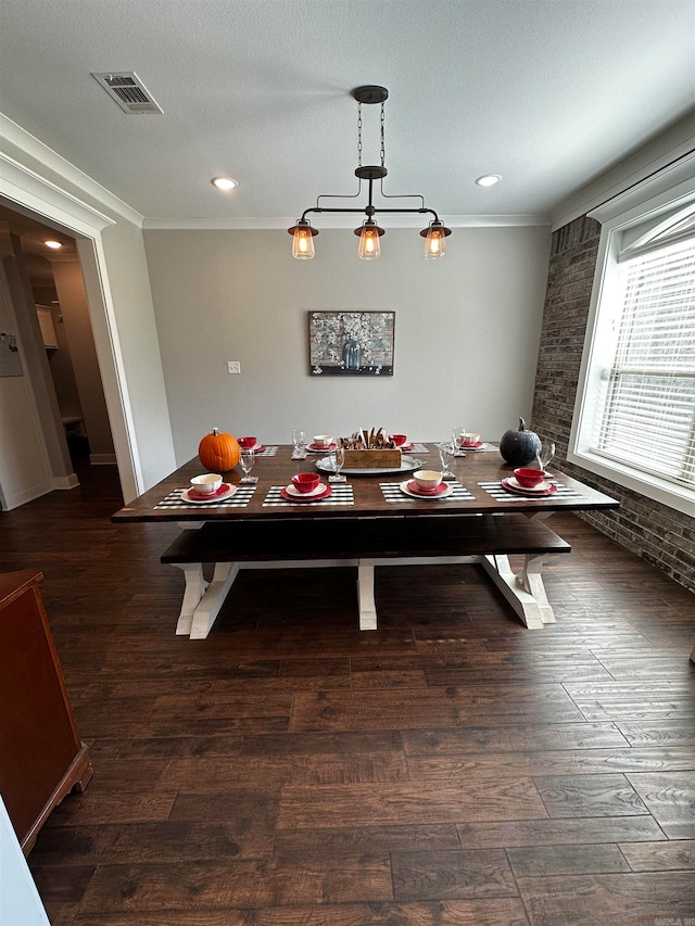 dining space with dark wood-type flooring, ornamental molding, and a textured ceiling