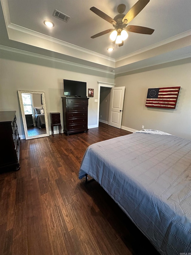 bedroom with ceiling fan, a tray ceiling, ornamental molding, and dark hardwood / wood-style flooring