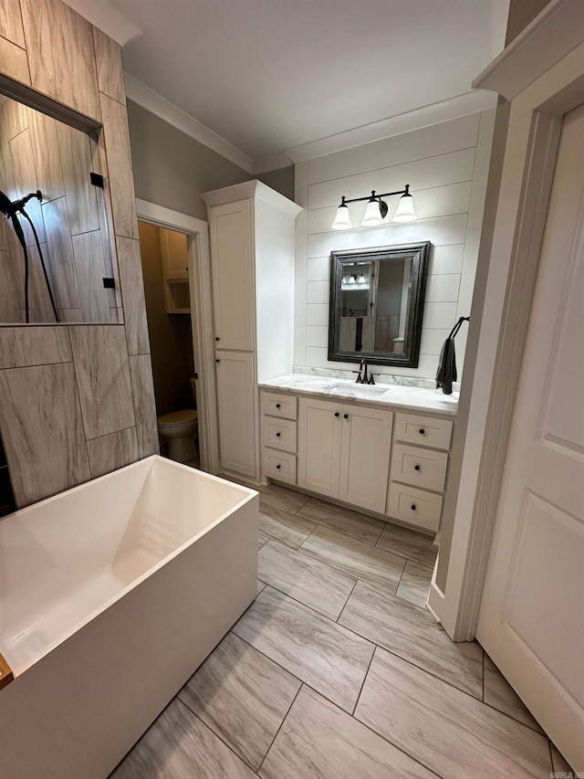 bathroom featuring toilet, ornamental molding, vanity, and a bathtub