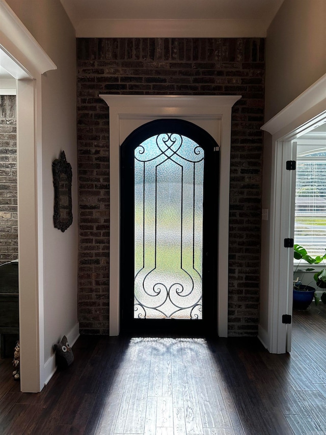 entryway with brick wall and dark wood-type flooring