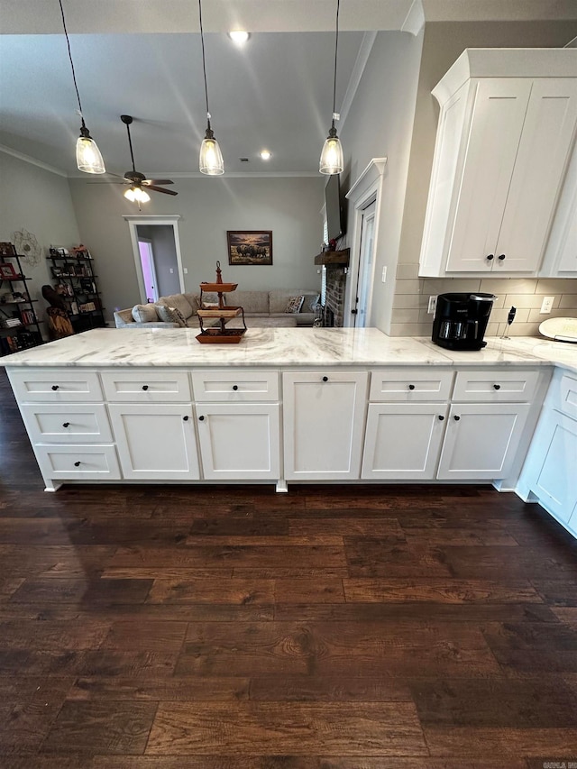 kitchen with decorative backsplash, white cabinetry, hanging light fixtures, and dark hardwood / wood-style flooring