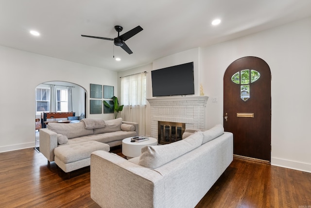 living room with dark hardwood / wood-style floors, ceiling fan, and a fireplace