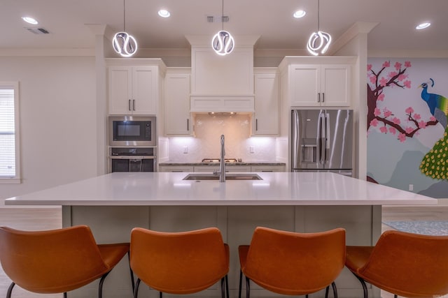 kitchen with tasteful backsplash, an island with sink, appliances with stainless steel finishes, a sink, and visible vents
