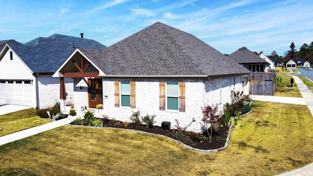 view of front of house featuring brick siding, a shingled roof, a front lawn, and a garage