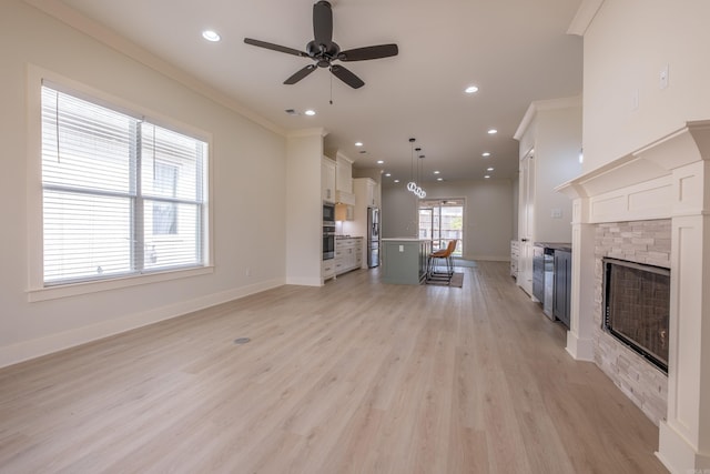 unfurnished living room with ceiling fan, baseboards, recessed lighting, light wood finished floors, and a stone fireplace