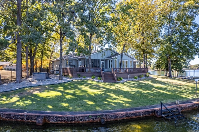 rear view of property featuring a deck with water view and a lawn