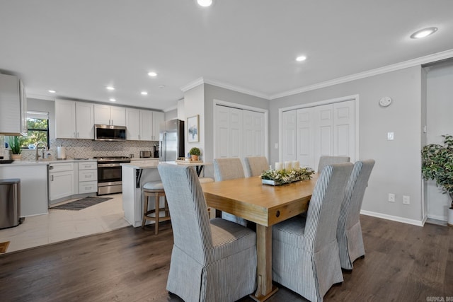 dining room featuring ornamental molding, sink, and dark hardwood / wood-style flooring