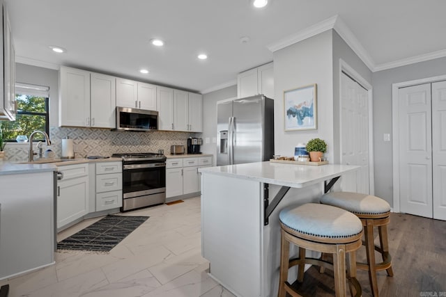 kitchen featuring a breakfast bar area, white cabinets, and stainless steel appliances