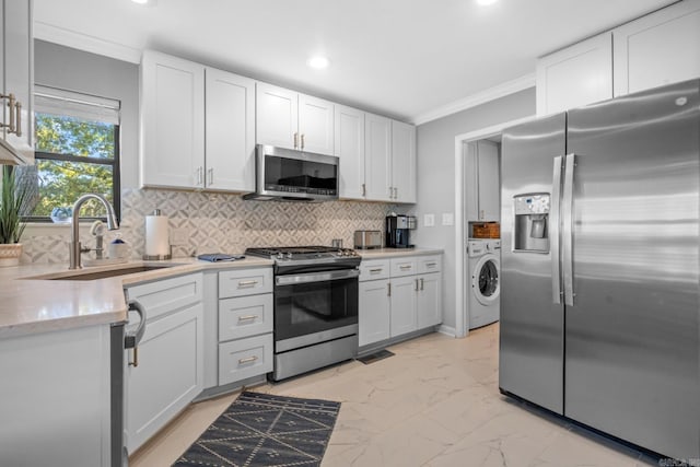 kitchen with stainless steel appliances, ornamental molding, sink, white cabinetry, and tasteful backsplash