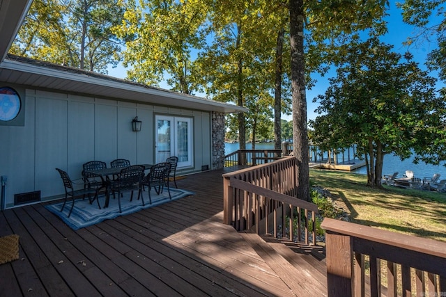 wooden deck with a water view and a lawn