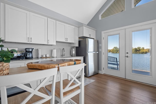 kitchen with french doors, dark hardwood / wood-style floors, stainless steel fridge, white cabinets, and high vaulted ceiling