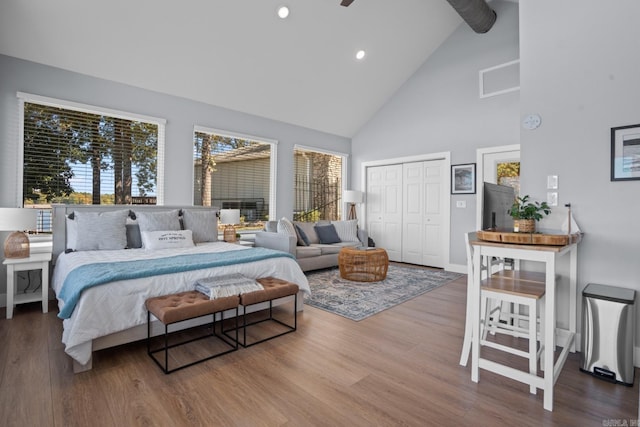 bedroom with a closet, high vaulted ceiling, and wood-type flooring