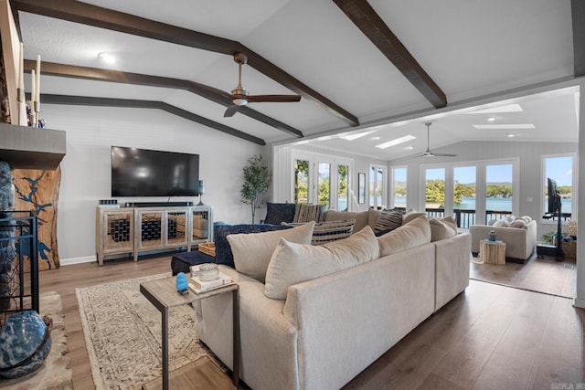 living room with a wealth of natural light, hardwood / wood-style floors, vaulted ceiling with beams, and french doors