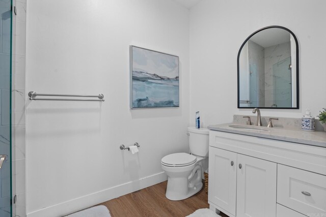 bathroom featuring toilet, an enclosed shower, hardwood / wood-style floors, and vanity