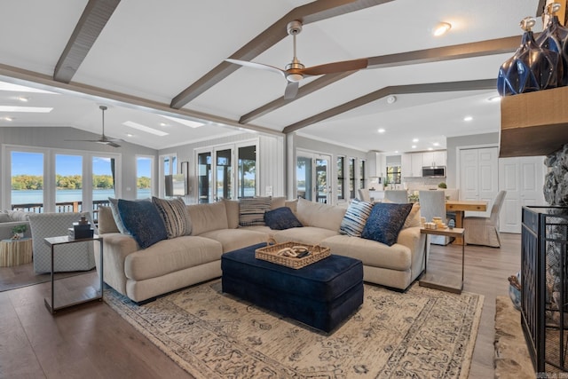 living room featuring light hardwood / wood-style floors, vaulted ceiling with beams, a water view, and a healthy amount of sunlight