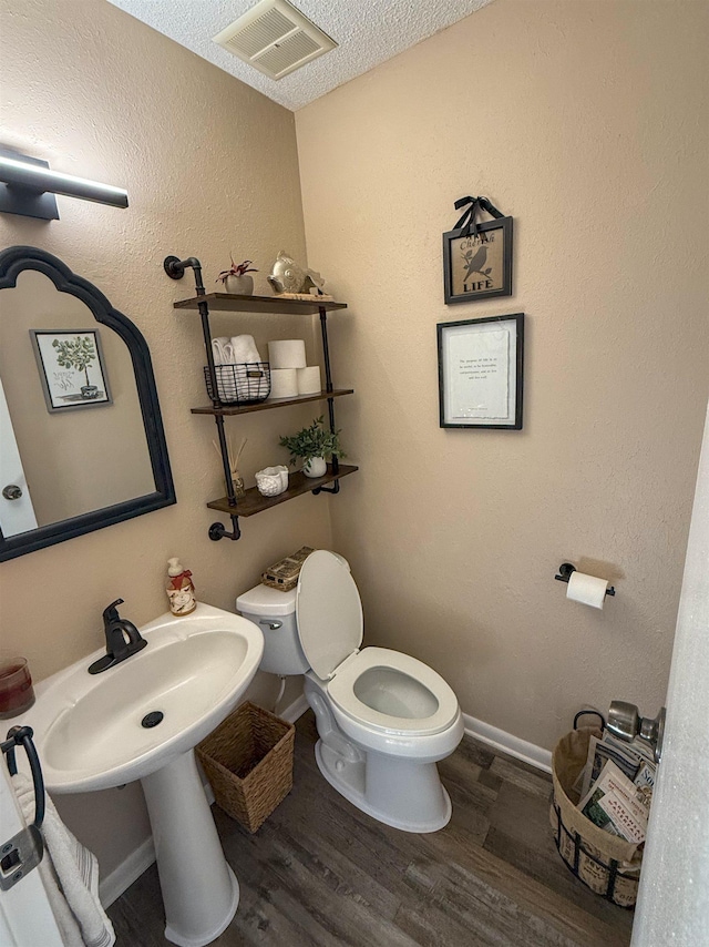 bathroom featuring toilet, a textured ceiling, and hardwood / wood-style floors