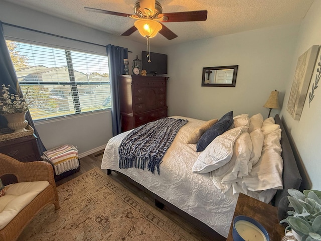 bedroom featuring ceiling fan, wood-type flooring, and a textured ceiling