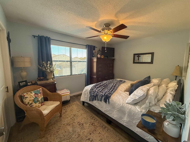 bedroom with a textured ceiling, wood-type flooring, and ceiling fan