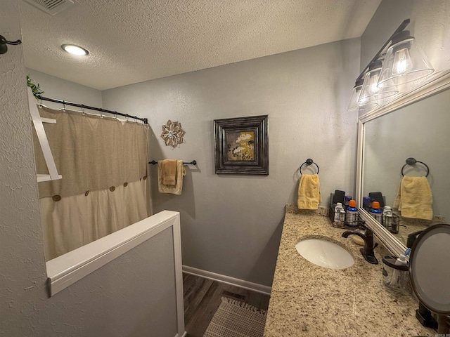 bathroom featuring vanity, hardwood / wood-style flooring, a textured ceiling, and curtained shower