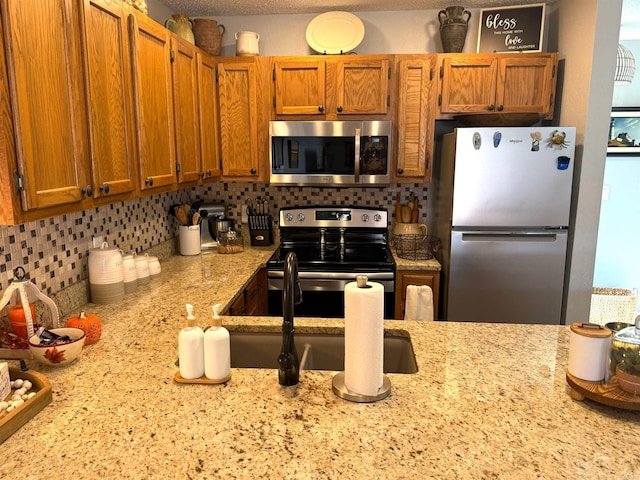 kitchen with tasteful backsplash, stainless steel appliances, and light stone countertops