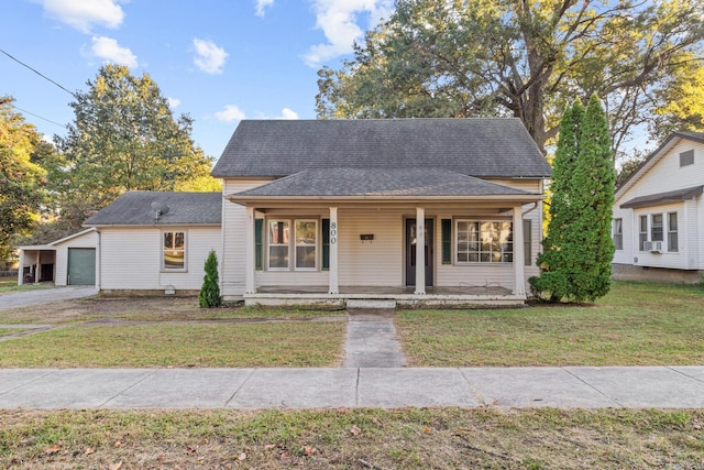 view of front of house featuring covered porch, a front yard, cooling unit, and a garage