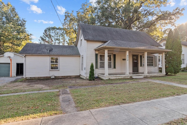 bungalow with covered porch, an outdoor structure, a garage, and a front lawn