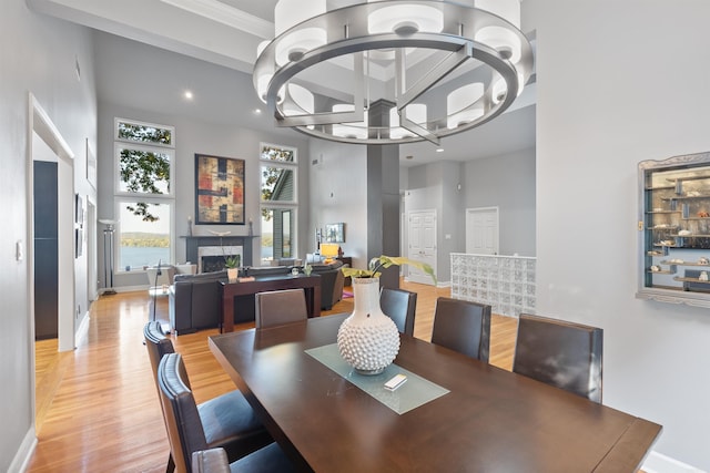 dining space with ornamental molding, a high ceiling, light hardwood / wood-style flooring, and a chandelier