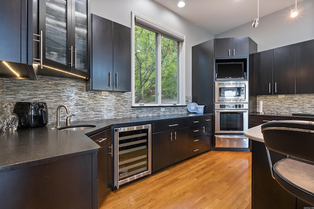 kitchen with tasteful backsplash, sink, beverage cooler, and stainless steel oven