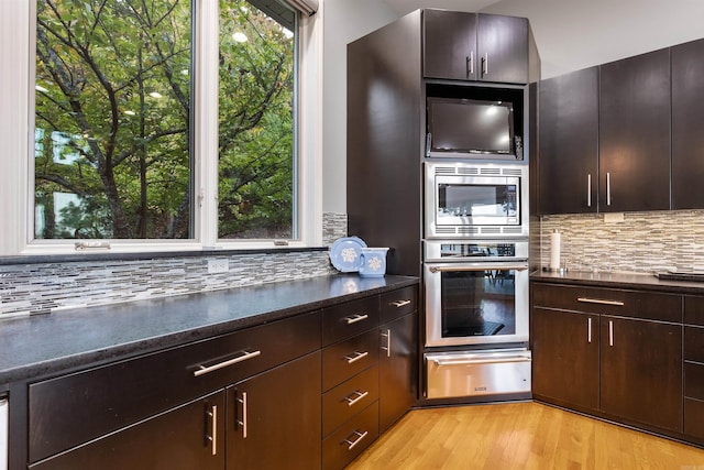 kitchen with plenty of natural light, appliances with stainless steel finishes, light wood-type flooring, and decorative backsplash