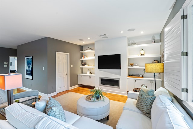 living room featuring built in shelves and light wood-type flooring