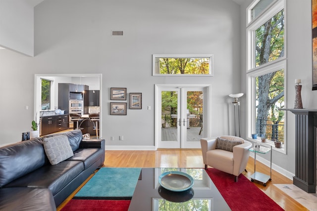 living room featuring light hardwood / wood-style floors, french doors, and a high ceiling