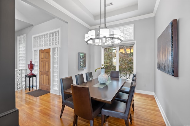 dining space with ornamental molding, hardwood / wood-style flooring, a chandelier, and a tray ceiling