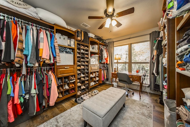 spacious closet with dark wood-type flooring and ceiling fan