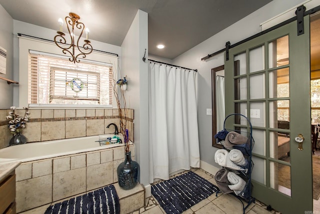 bathroom with an inviting chandelier, tile patterned flooring, and tiled tub