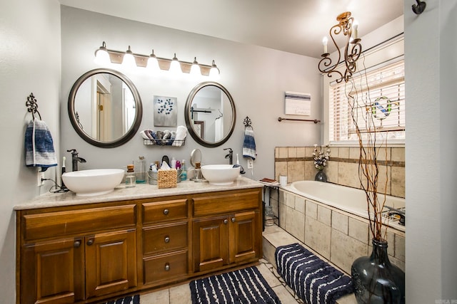 bathroom featuring vanity, an inviting chandelier, tile patterned flooring, and tiled bath